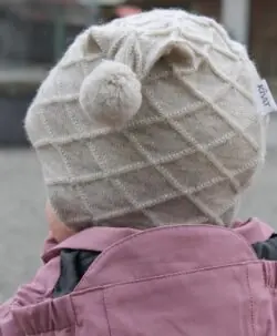 Alternative view of KIVAT foret kabelstrikket ullue med knyting og to henge dusker ufarget Sand