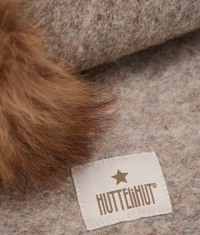 Supersøt og varm balaclava med dusker i tovet ull (80% ull og 20% polyester) fra HUTTEliHUT. Foret er laget av myk bomullsvelour som gjør den ekstra varm og vindtett på kalde dager. Ribbekanten rundt ansiktet er i bomull som gjør at den ikke klør. Vaskes fint på 30 grader ullprogram med vaskemiddel for ull/silke. Tørkes flatt. Om duskene: Dusken er laget av pels fra Alpakkaer fra Bolivia etter fairtrade prinsipper. Duskene er ikke farget og kan derfor ha litt ulik størrelser og nyanser fra lue til lue. Alpakkaen er mer verdifull når den er i live og kan leve i opptil 20-25 år. Når den dør nyttiggjør man seg av hele dyret også pelsen.