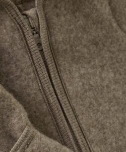 Smart og varm HUTTEliHUT dress i ullfleece. HUTTEliHUT dressen har en fast hette med en rund hodeform med små søte ører. Den har lange ermer og ben med praktiske folder opp til størrelse 80 for å holde små føtter og hender varme. Den har ribbekanter i alle åpninger. Den åpnes foran med en skjult glidelås med hakebeskyttelse. Laget av 100% merinoull. Dette produktet er kjent for sin holdbarhet hvis det behandles riktig: Vask det kun når det er nødvendig. Velg et skånsomt ullvaskemiddel. Ikke bruk tøymykner. Velg alltid skånsom ullvask i maskin, og vreng plagget på vrangen. Bruk et lavt sentrifugeringsprogram. Form plagget mens det er vått. Bruk lunkent vann til håndvask, og unngå å vri det opp. Trykk forsiktig med et håndkle for å fjerne overflødig vann. Legg flatt på et håndkle for å tørke – ikke legg på en radiator eller i en tørketrommel.