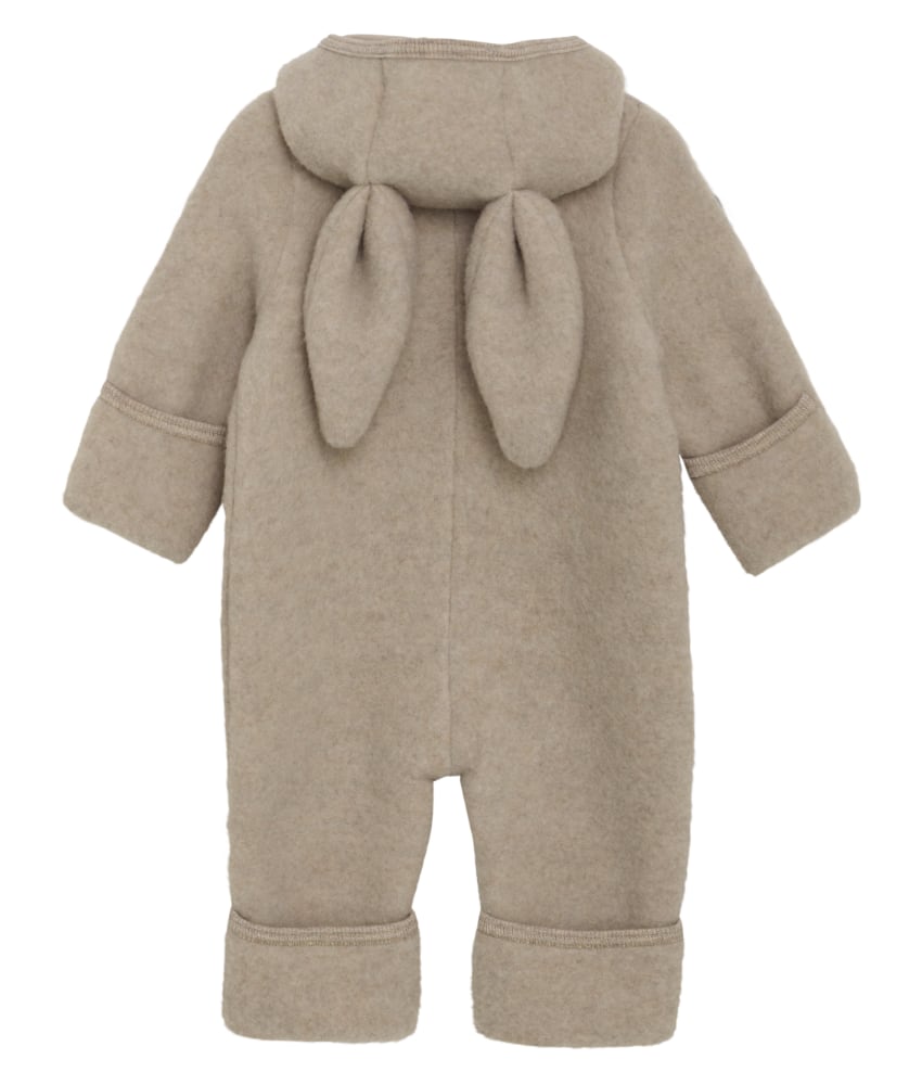 Smart og varm HUTTEliHUT alt-i-ett-dress laget av ullfleece. HUTTEliHUT-dressen har en fast hette med avrundet form og søte små kaninører på toppen. Barnevogndressen har lange ermer og ben med praktiske folder opptil størrelse 80 for å holde små føtter og hender varme. Alle åpninger har ribbekanter. Dressen åpnes foran med en skjult glidelås og hakebeskyttelse. Laget av 100% merinoull. Dette produktet er kjent for sin holdbarhet hvis det behandles riktig: Vask det kun når det er nødvendig. Velg et skånsomt ullvaskemiddel. Ikke bruk tøymykner. Velg alltid skånsom ullvask i maskin og vreng plagget på vrangen. Bruk et lavt sentrifugeringsprogram. Form plagget mens det er vått. Bruk lunkent vann til håndvask, og unngå å vri det opp. Trykk forsiktig med et håndkle for å fjerne overflødig vann. Legg flatt på et håndkle for å tørke – ikke legg på en radiator eller i en tørketrommel.