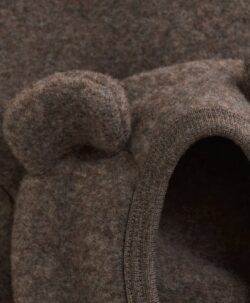 Nydelig HUTTEliHUT jakke i ullfleece. Jakken har en fast hette med søte bamseører. Den har lange ermer og smale myke ribbekanter i alle åpninger. Jakken åpnes foran med glidelås med hakebeskyttelse. Laget av 100% merinoull.  Dette produktet er kjent for sin holdbarhet hvis det behandles riktig: Vask det kun når det er nødvendig. Velg et skånsomt ullvaskemiddel. Ikke bruk tøymykner. Velg alltid skånsom ullvask i maskin og vreng plagget på vrangen. Bruk et lavt sentrifugeringsprogram. Form plagget når det er vått. Bruk lunkent vann for håndvask og unngå å vri det opp. Trykk forsiktig med et håndkle for å fjerne overflødig vann. Legg flatt på et håndkle for å tørke – ikke legg på en radiator eller i en tørketrommel.