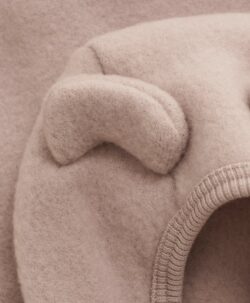 Nydelig HUTTEliHUT jakke i ullfleece. Jakken har en fast hette med søte bamseører. Den har lange ermer og smale myke ribbekanter i alle åpninger. Jakken åpnes foran med glidelås med hakebeskyttelse. Laget av 100% merinoull.  Dette produktet er kjent for sin holdbarhet hvis det behandles riktig: Vask det kun når det er nødvendig. Velg et skånsomt ullvaskemiddel. Ikke bruk tøymykner. Velg alltid skånsom ullvask i maskin og vreng plagget på vrangen. Bruk et lavt sentrifugeringsprogram. Form plagget når det er vått. Bruk lunkent vann for håndvask og unngå å vri det opp. Trykk forsiktig med et håndkle for å fjerne overflødig vann. Legg flatt på et håndkle for å tørke – ikke legg på en radiator eller i en tørketrommel.